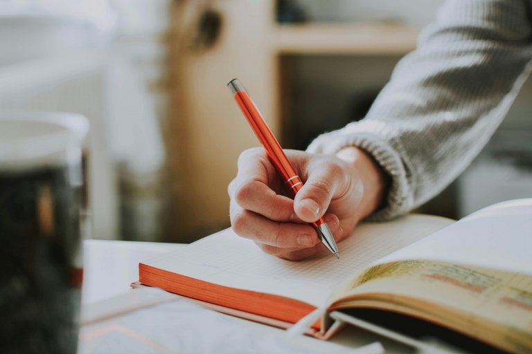 eine schreibende Hand mit rotem Stift